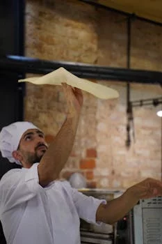 experienced pizza chef tossing dough skillfully